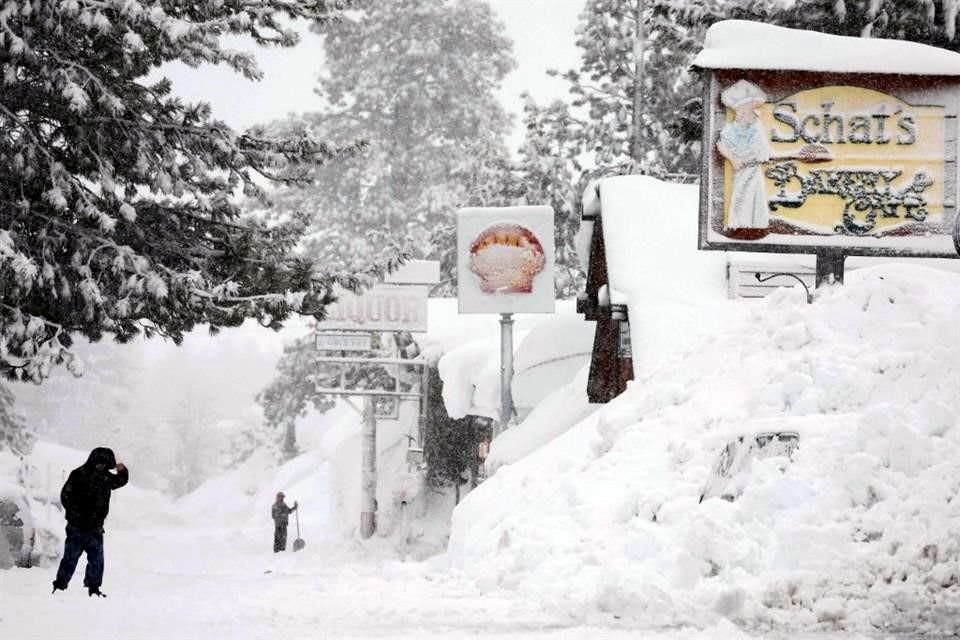 Una persona camina mientras la nieve cae sobre los bancos de nieve acumulados de tormentas anteriores durante otra tormenta de invierno en las montañas de Sierra Nevada.