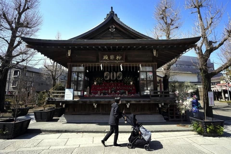 Una mujer empuja a su hija frente a una sala que exhibe muñecas 'hina' en un santuario sintoísta en Tokio.