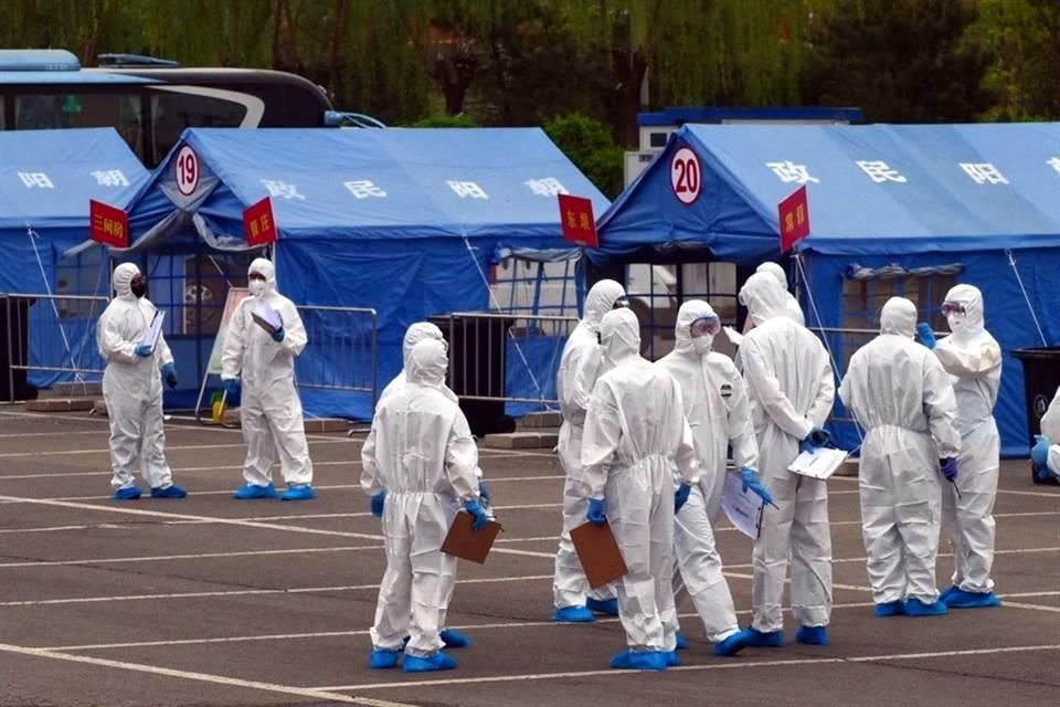 Trabajadores del Gobierno frente a una carpa azul utilizada para coordinar el transporte de viajeros desde Wuhan a sitios de cuarentena designados en Beijing.