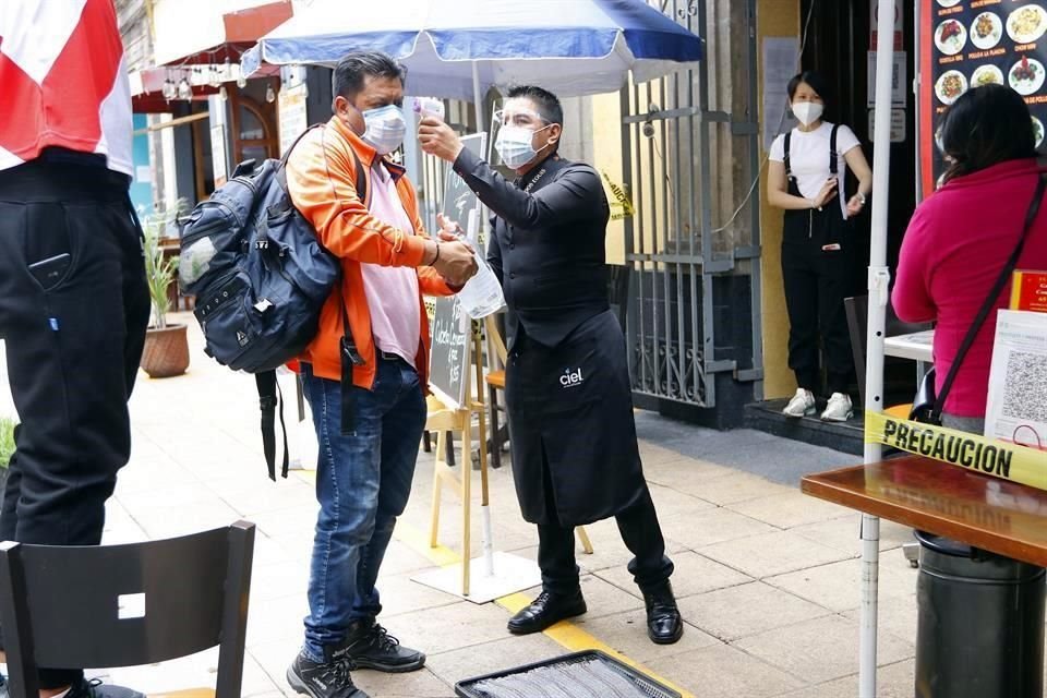 Un mesero toma la temperatura a un comensal, en el Centro Histórico.