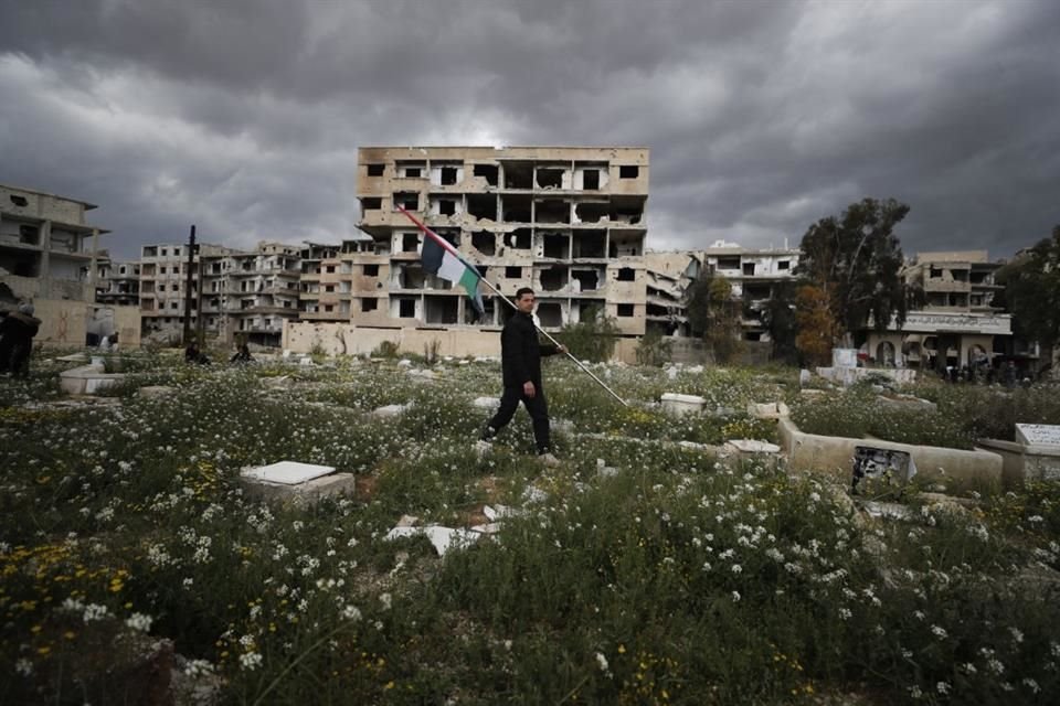 Un hombre carga una bandera palestina durante el funeral de Ali Ramzi al-Aswad, un comandante del grupo armado palestino Yihad Islámico, en el campamento para refugiados Yarmouk, en Damasco, Siria.