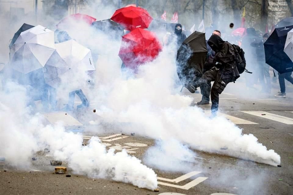 Un manifestante patea el gas lacrimógeno lanzado por la policía antidisturbios al margen de una manifestación por la reforma de Macron.