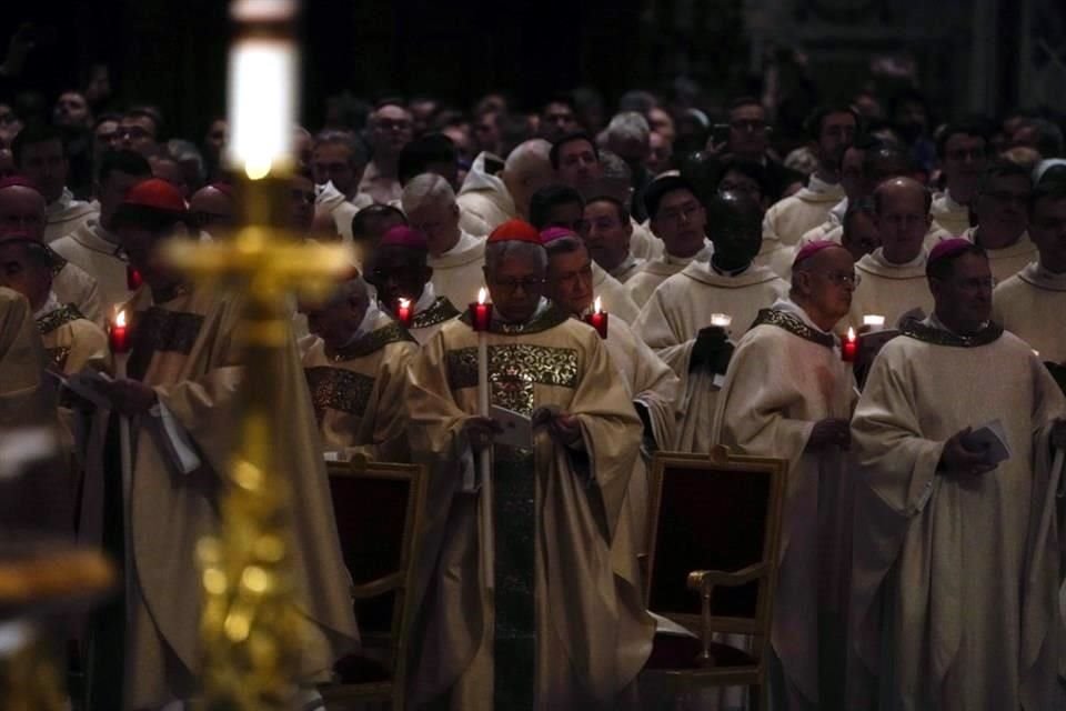 Los cardenales sostienen velas mientras el Papa Francisco preside la ceremonia de vigilia de Pascua.