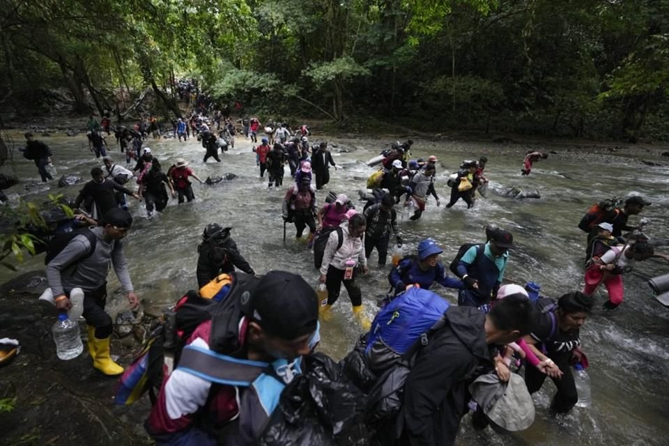 Migrantes, la mayoría venezolanos, cruzan un río durante su travesía a través de la selva del Darién en octubre del 2022.