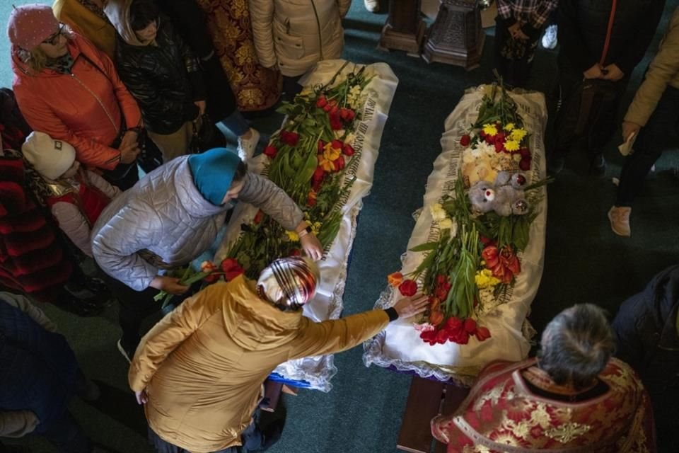 Familiares y amigos lloraron junto a los ataúdes de niños y otras personas que murieron en un ataque con un misil ruso en Uman.