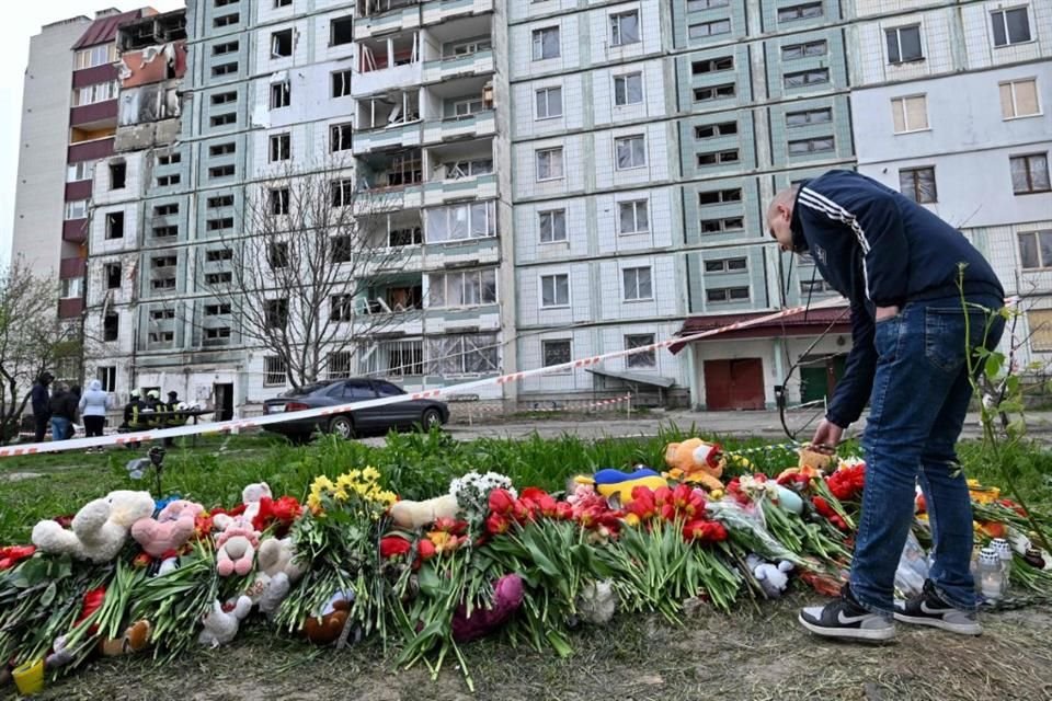 Un hombre dejando flores frente a un edificio dañado por un ataque ruso con misil, en Uman.