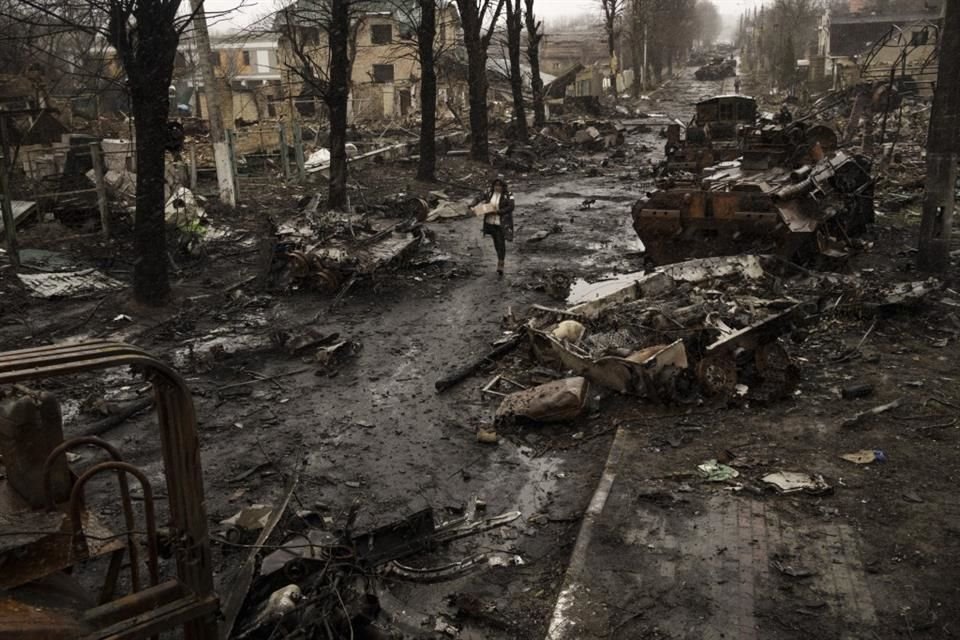 Una mujer camina en medio de tanques rusos destruidos, el 3 de abril de 2022, en Bucha, a las afueras de Kiev, Ucrania.