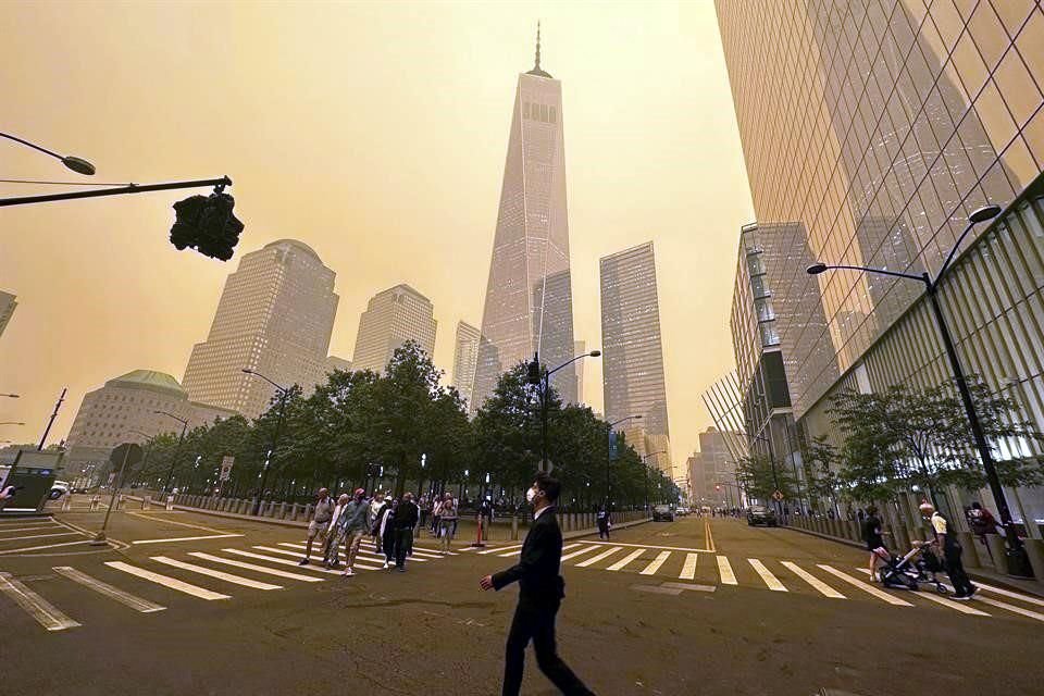 Transeúntes caminan frente al One World Trade Center en medio de la humareda por los incendios forestales de Canadá.