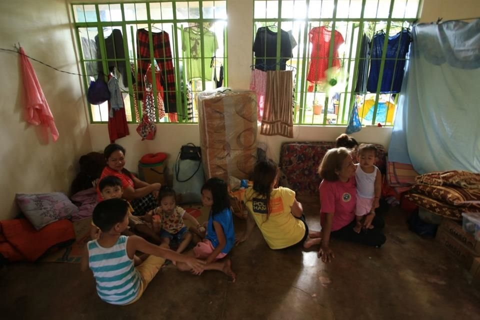 Personas descansan en la escuela primaria Gabawan, usada como centro de evacuación tras la actividad del Monte Mayón.