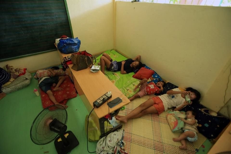 Personas descansan en la escuela primaria Gabawan, usada como centro de evacuación tras la actividad del Monte Mayón.