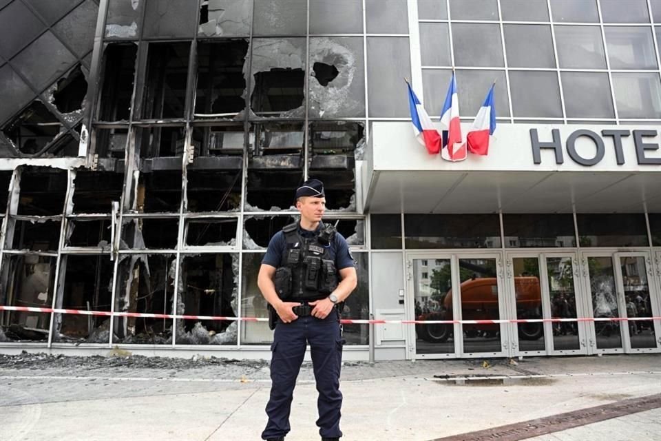 Un oficial de policía se para frente a la fachada quemada del Hotel du ville en Garges-les-Gonesse, al norte de París.