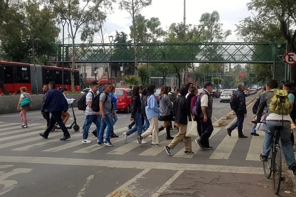 La mayor parte cruza sobre el paso de cebra en el pavimento y una pequeña parte cruza sobre el puente.