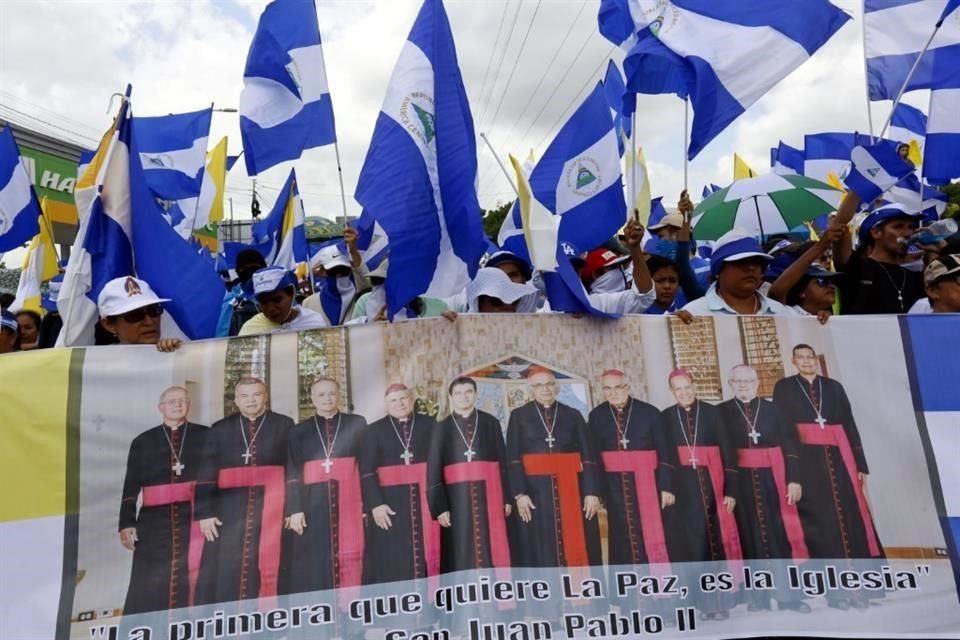 Manifestantes antigubernamentales sostienen una pancarta con un grupo de cardenales católicos.