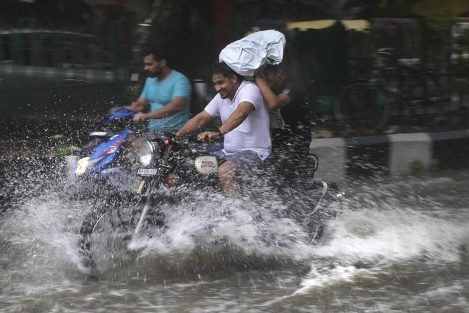 Un motociclista atraviesa una calle inundada de agua durante un fuerte aguacero en Nueva Delhi.