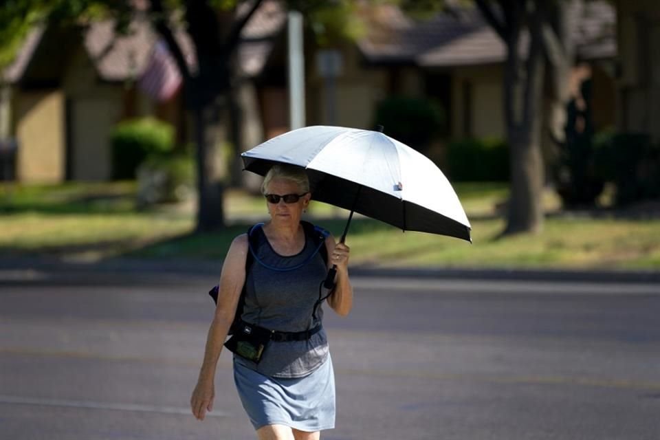 Una mujer se protege del sol con una sombrilla en Phoenix, Arizona, el 10 de julio del 2023.