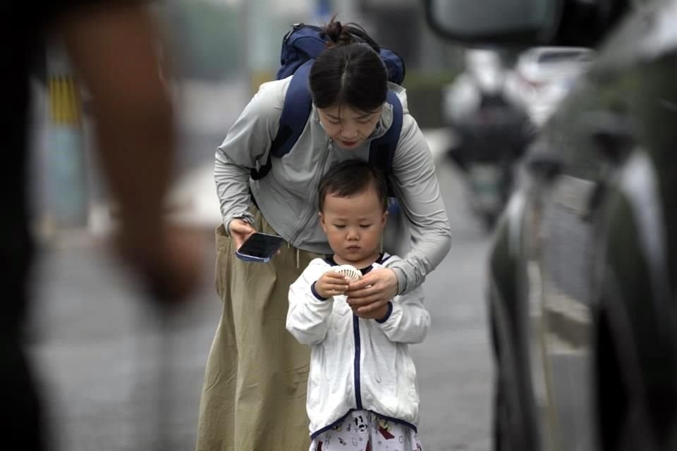 Una mujer ayuda a un niño a encender un ventilador eléctrico en un día caluroso en Beijing.