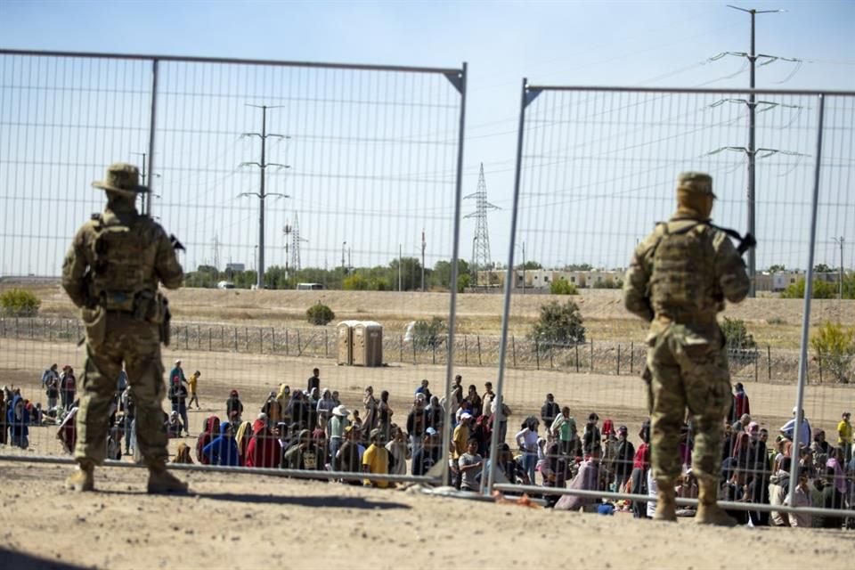 Migrantes esperan frente a miembros de la Guardia Nacional de Texas, en El Paso, el 10 de mayo del 2023.