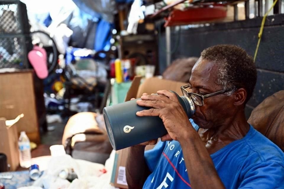 Warren Smith, un veterano del Ejército de EU, bebe agua mientras está sentado a la sombra con amigos en 'The Zone', un vasto campamento para personas sin hogar.