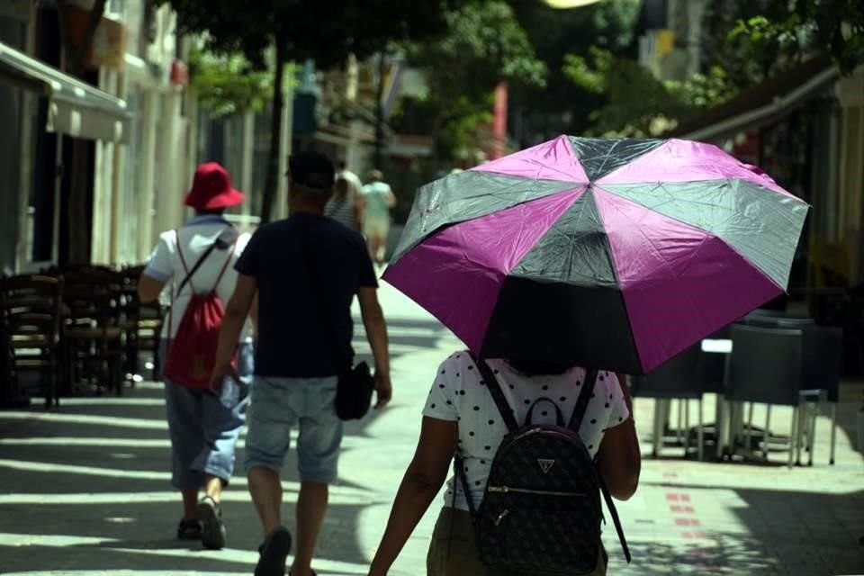 Una mujer se protege del sol con un paraguas durante un día caluroso en la calle comercial peatonal Ledras en la capital Nicosia, Chipre.