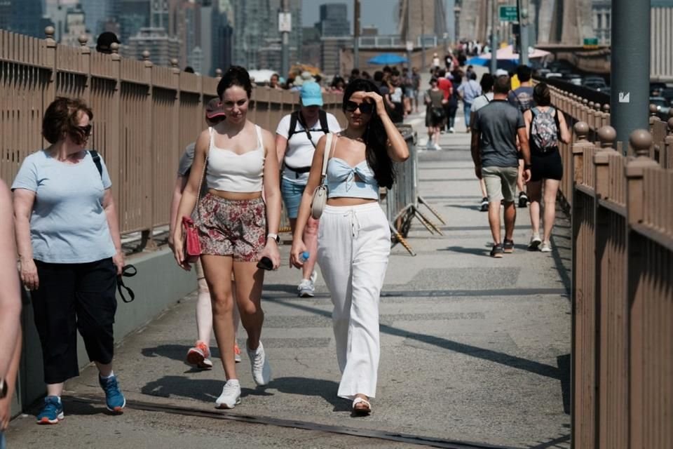 Personas caminan por el puente de Brooklyn en la ciudad de Nueva York, durante una ola de calor.