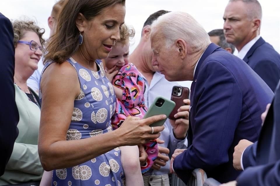 El Presidente Joe Biden habla con un niño mientras saluda a los miembros del personal de la embajada y sus familias.