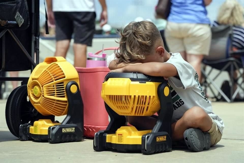 Braxton Hicks, de Livingston, Texas, mantiene su cara sobre un abanico portátil para refrescarse ante el intenso calor.