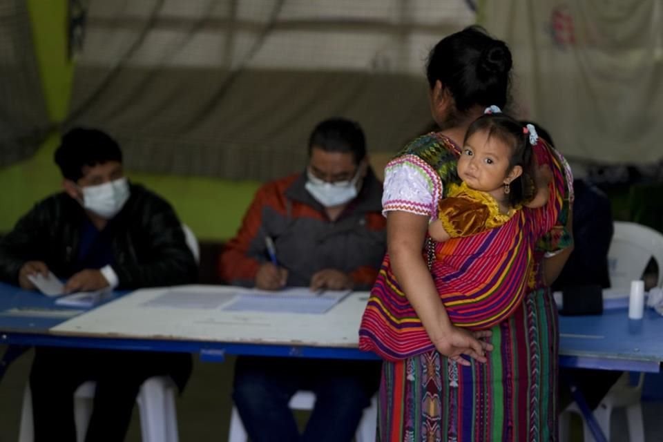 Una mujer acude a votar cargando a su hija en Santa Maria Cauque, en Guatemala.