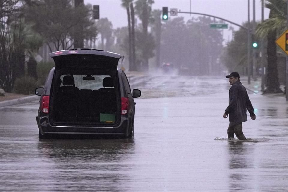 Un conductor acude a retirar pertenencias de su vehículo tras quedar varado en una calle inundada, el 20 de agosto de 2023 en Palm Desert, California.