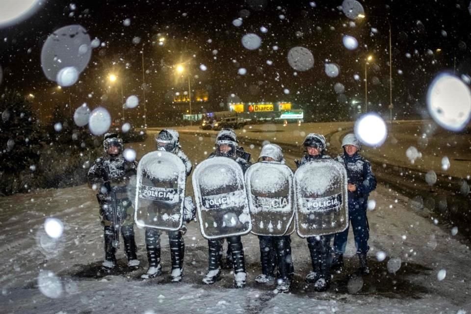 Agentes de policía custodian un supermercado bajo la nieve que cae después de un intento de saqueo, en Bariloche, provincia de Río Negro, Argentina.