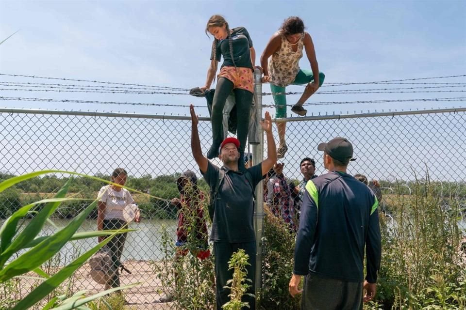 Migrantes se ayudan a cruzar un alambre de púas en la frontera entre México y Estados, el 25 de agosto.