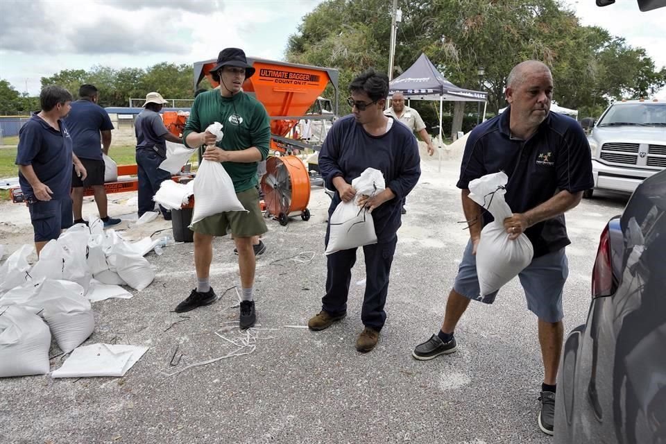 Miembros del Departamento de Parques y Recreación de Tampa, Florida, ayudan a los residentes a cargar sacos de arena ante la llegada del huracán 'Idalia'.