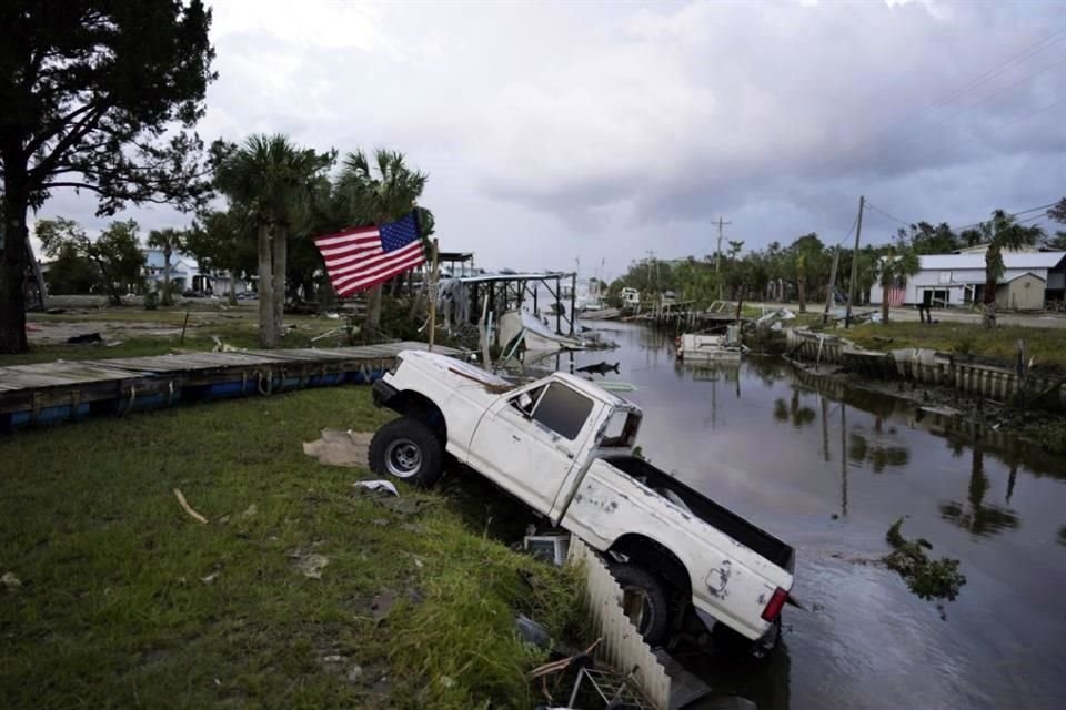 Una camioneta con una bandera estadounidense atada se encuentra a medio camino de un canal en Horseshoe Beach, Florida.