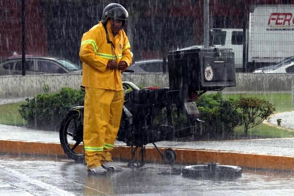 Un motociclista fue sorprendido por la lluvia mientras arreglaba su motocicleta.