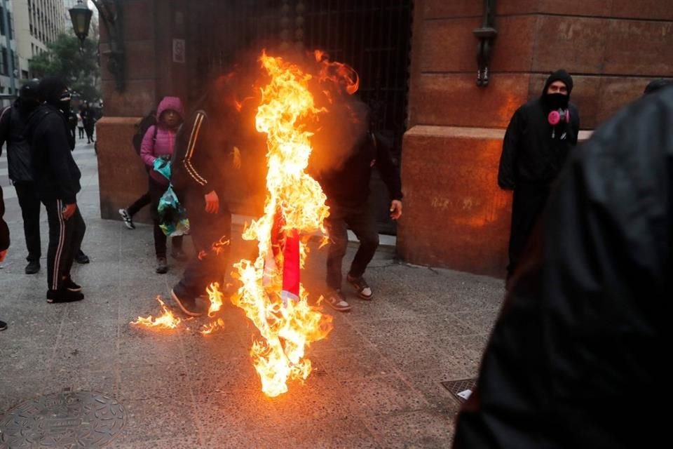 Manifestantes queman una bandera chilena durante la marcha del 50 aniversario del golpe de estado, liderado por el General Augusto Pinochet.