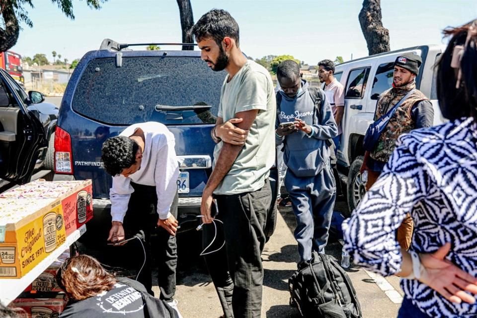 Migrantes esperan ser transportados a un refugio tras cruzar la frontera en San Ysidro, California.