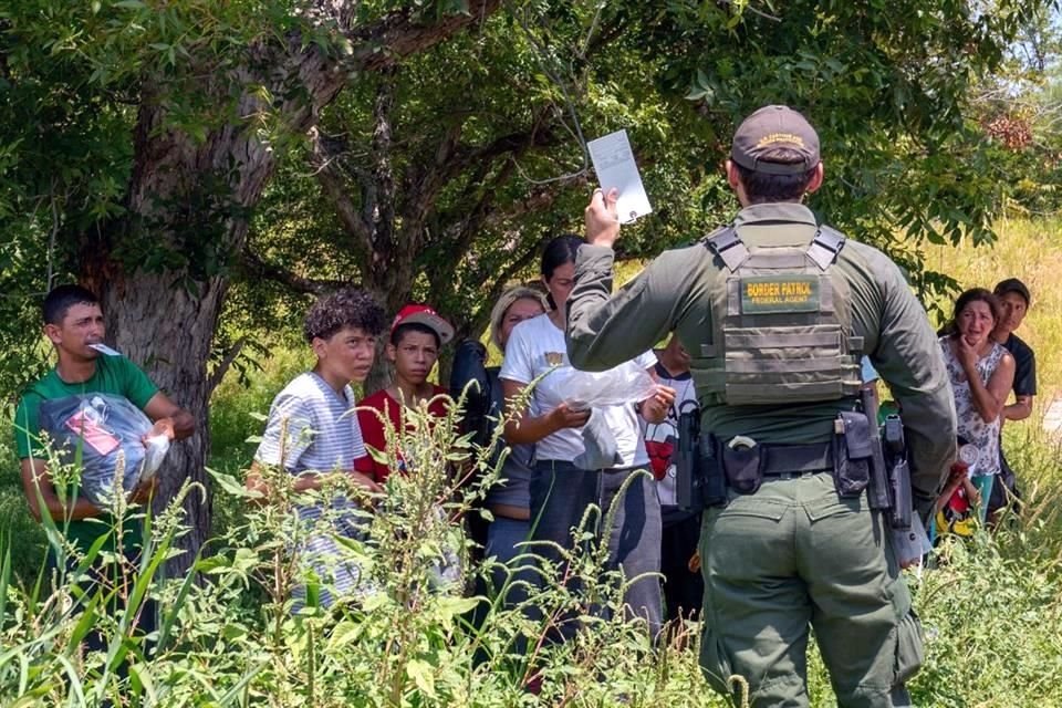 Un grupo de migrantes que cruzaron a Estados Unidos desde México en Eagle Pass, Texas, escuchan instrucciones dadas por un agente de la Patrulla Fronteriza.