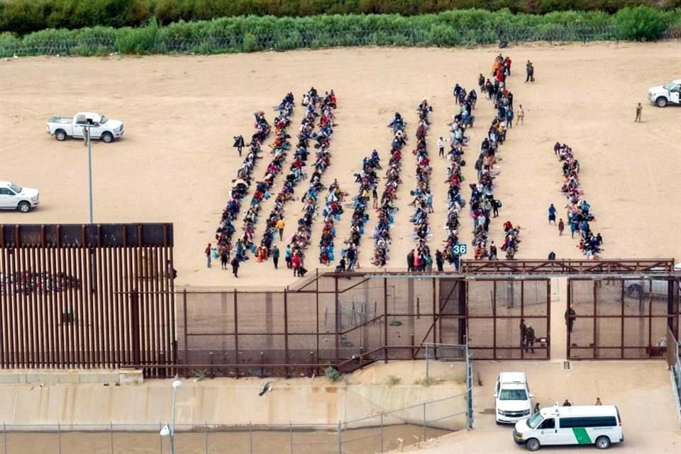 Migrantes esperan agrupados del lado de Ciudad Juárez en busca de asilo de Estados Unidos.