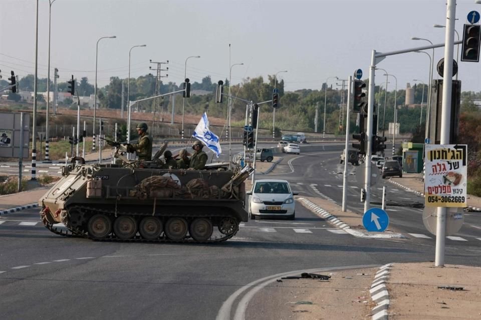 Las fuerzas israelíes cruzan una carretera principal en su vehículo blindado de transporte de personal (APC) mientras se despliegan tropas adicionales cerca de la ciudad sureña de Sderot.