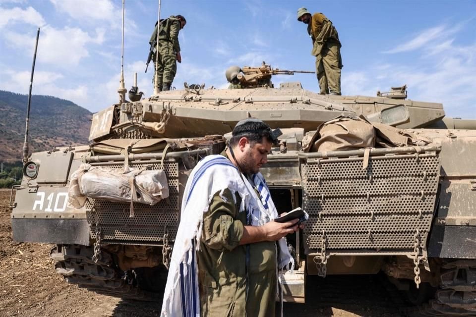 Un sodleir israelí reza frente a un tanque Merkava en las afueras de la ciudad norteña de Kiryat Shmona, cerca de la frontera con el Líbano, el 8 de octubre de 2023.