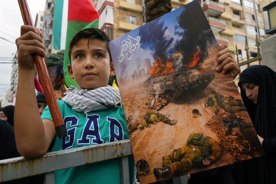 Un niño sostiene un cartel que muestra un tanque israelí en llamas y soldados muertos en el suburbio de Dahiyeh, en el sur de Beirut, Líbano.