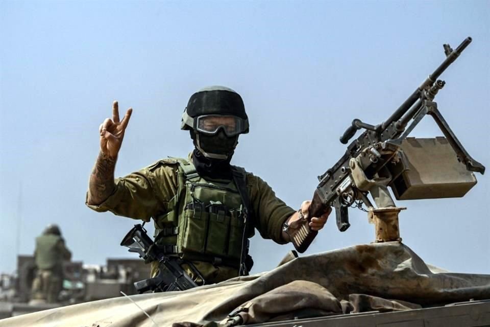 Un soldado del Ejército israelí saluda mientras maneja una torreta encima de un vehículo blindado cerca de la frontera de Gaza.