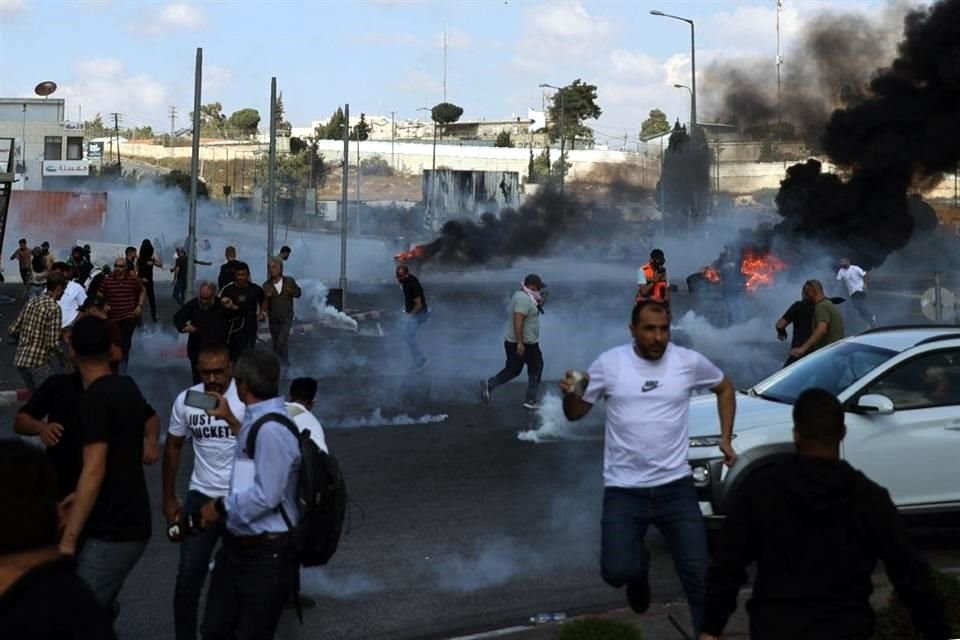 Los palestinos se dispersan durante los enfrentamientos con los soldados israelíes en la entrada norte de la ciudad palestina de Ramallah.