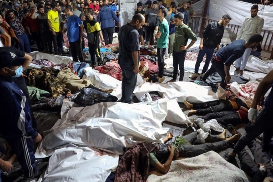 Personas reunidas alrededor de los cuerpos de palestinos muertos en ataques aéreos israelíes contra el hospital árabe Ahli en el centro de Gaza después de ser transportados al hospital Al-Shifa.