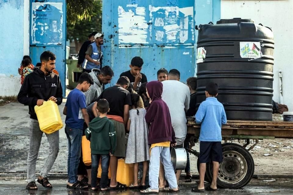 Hombres y niños llegan con galones para llenar agua de una cisterna portátil montada en un carro en Rafah, en el sur de la Franja de Gaza.