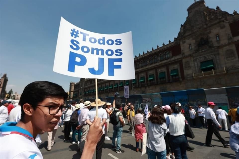 Un joven sostiene un cartel frente a Palacio Nacional con la leyenda: 'Todos somos PJF'.