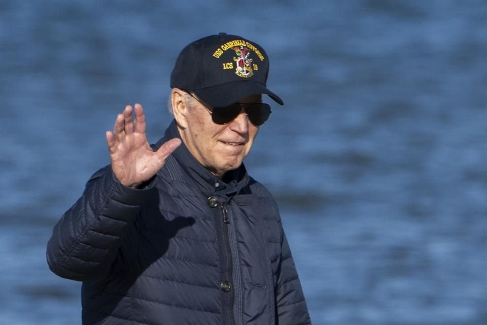 El Presidente Joe Biden saluda mientras camina por la playa con la Primera Dama, Jill Biden.