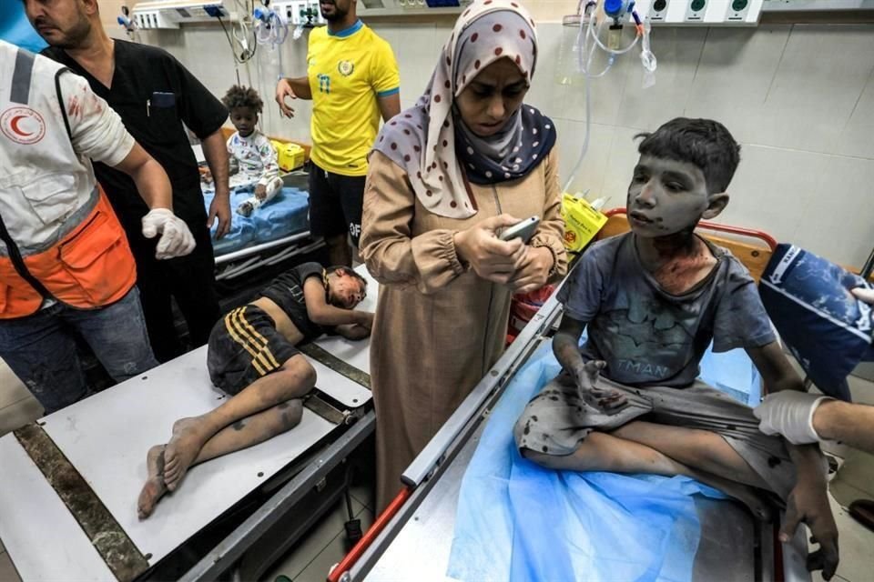 Una mujer usa un teléfono mientras espera con dos niños heridos en un bombardeo israelí a punto de recibir tratamiento de emergencia en una sala de traumatología del hospital Nasser en Khan Yunis.