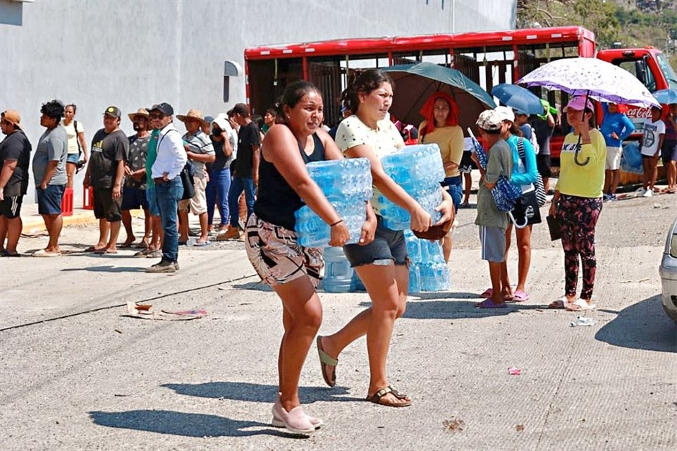 Damnificados por el huracán 'Otis' cargan paquetes con agua embotellada que les servirá para cocinar y beber