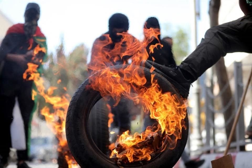 Jóvenes palestinos queman neumáticos durante enfrentamientos con las fuerzas de seguridad israelíes tras una protesta en apoyo a Gaza.