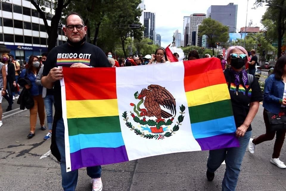 Un hombre y una mujer portan la bandera de México con los colores de bandera de la población LGBT+